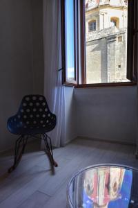 a chair and a glass table in a room with a window at Quaint Boutique Hotel Sannat in Sannat