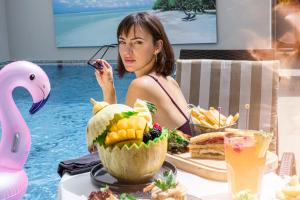 une femme assise à une table devant une piscine dans l'établissement Idou Anfa Hôtel & Spa, à Casablanca