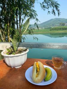 dwa hot dogi i banany na stole z doniczką w obiekcie Hahaland w mieście Phong Nha