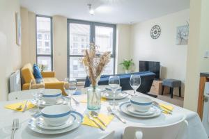 a dining room with a table with plates and wine glasses at Stay in our Stylish Flat! & secure building & sleeps up to 4 in Birmingham