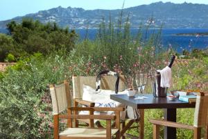 een tafel en stoelen op een patio met uitzicht op het water bij Park Hotel & Spa Cala Di Lepre in Palau