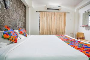 um quarto com uma grande cama branca com almofadas coloridas em Hotel JK Lions - Koradi, Nagpur em Nagpur