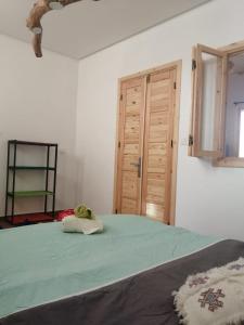een slaapkamer met een groen bed en een houten deur bij Jolie Appartement in Agadir