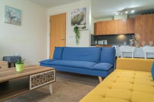 a living room with a blue couch and a kitchen at Stay in our Stylish Flat! & secure building & sleeps up to 4 in Birmingham