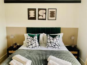 a bedroom with a bed with a green headboard and pillows at Just £45pppn! Prime Comfort for Contractors with Spacious Parking, Plush Beds, Top-notch Amenities, Flexible Stays & Lightning-Fast Internet in Woking