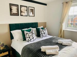 een slaapkamer met een bed met groene en witte kussens bij Just £45pppn! Prime Comfort for Contractors with Spacious Parking, Plush Beds, Top-notch Amenities, Flexible Stays & Lightning-Fast Internet in Woking