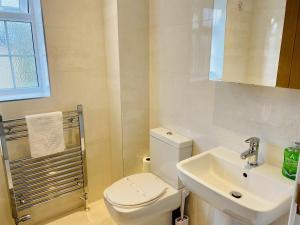 a white bathroom with a toilet and a sink at Just £45pppn! Prime Comfort for Contractors with Spacious Parking, Plush Beds, Top-notch Amenities, Flexible Stays & Lightning-Fast Internet in Woking