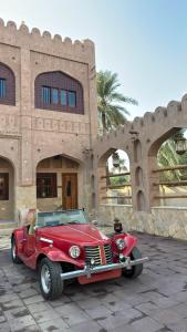 a red car parked in front of a building at Aldar Inn in Nizwa