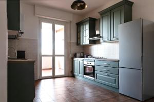 uma cozinha com armários verdes e um frigorífico branco em DeHomes - Papa Giovanni XXIII em Buccinasco