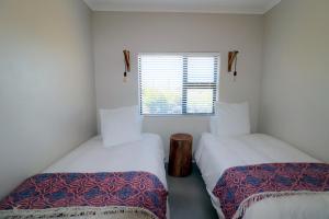 two beds in a small room with a window at Karen Close 3219 in Struisbaai