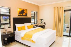 a bedroom with a large white bed with yellow pillows at Heavenly Boutique Hotel in Johannesburg