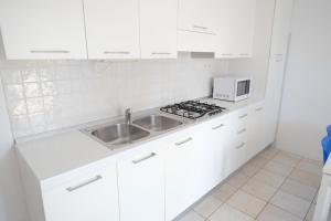 eine weiße Küche mit einer Spüle und einer Mikrowelle in der Unterkunft Marina Village Apartments in Lido di Jesolo