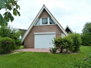 uma casa com um telhado de gambrel e uma garagem em Knechtsand em Dorum Neufeld