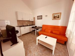 a living room with an orange couch and a kitchen at Bungalows Doble UVE in Tías