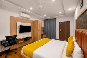 a bedroom with a bed and a desk and a television at Gateway Premium Inn in Bangalore