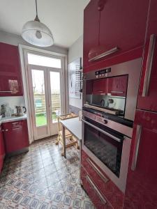a kitchen with red cabinets and a stove and a table at Choisy-le-Roi : luxe olympique in Choisy-le-Roi