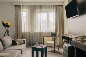 een woonkamer met een bank en stoelen en een televisie bij Oranje Hotel Leeuwarden in Leeuwarden