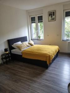 een slaapkamer met een bed met een gele sprei en 2 ramen bij City-Apartment in Krefeld, Küche, nähe Düsseldorf Messe in Krefeld