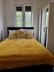 een slaapkamer met een geel bed en 2 ramen bij City-Apartment in Krefeld, Küche, nähe Düsseldorf Messe in Krefeld