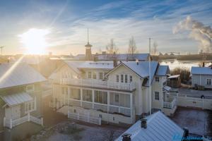 ein großes weißes Haus mit der Sonne im Hintergrund in der Unterkunft TurusenSaha Guesthouse in Oulu