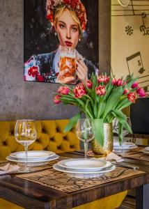 einen Tisch mit Tellern und Gläsern und ein Bild einer Frau in der Unterkunft Hotel Zielonki in Zielonki