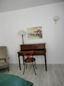 einen Schreibtisch in einem Zimmer mit einem Stuhl und einem Tisch in der Unterkunft Les Mulotières in Olivet