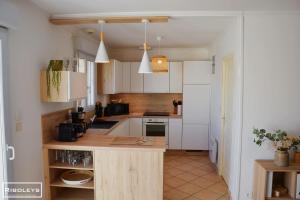 a kitchen with white cabinets and a wooden counter top at Vias Plage - Villa avec piscine privé in Vias