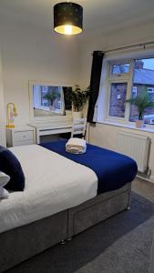 een slaapkamer met een bed met een blauwe deken en 2 ramen bij The Heart - Cosy 3 bedroom house with double driveway and Garden in Manchester in Manchester