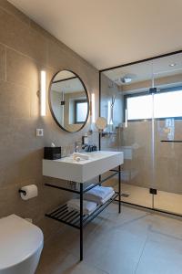 a bathroom with a sink and a toilet and a mirror at Pestana Amsterdam Riverside in Amsterdam