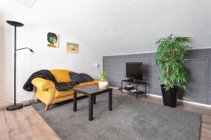 - un salon avec un canapé jaune et une télévision dans l'établissement De Entos, à Zandvoort