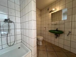 a bathroom with a tub and a toilet and a sink at Gasthaus zur Schwarzen Olive Zimmer 12 in Erlangen