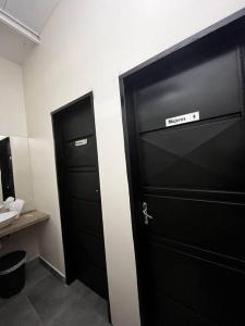 ein Badezimmer mit zwei schwarzen Türen und einem Waschbecken in der Unterkunft Casa Quincho con Piscina in Luque