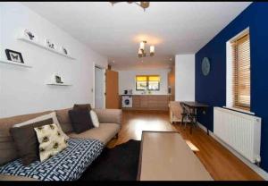 uma sala de estar com um sofá e uma parede azul em Large Two Bed Maisonette next to Station em Brentwood