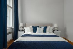 a bedroom with a blue and white bed with two windows at AIRSTAY PRAGUE apartment Vinohrady in Prague