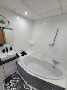 a white bathroom with a tub and a sink at Apartment next to Steel Arena in Košice