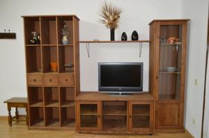 a television on a wooden entertainment center with shelves at Apartamento Casa Farras in Bonansa