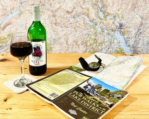 a bottle of wine and a book and a glass of wine at Cottage On The Brook in Keswick