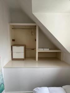 a room with a shelf under the stairs with a bed at Single room in shared flat Valley Hill, Loughton in Loughton