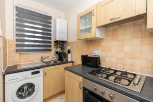 a kitchen with a stove top oven next to a washing machine at Tranquil 1BR in South Bank with onsite parking in London