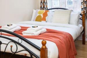 a bed with white and orange blankets and pillows at Tranquil 1BR in South Bank with onsite parking in London