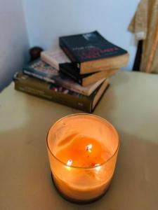 una vela en un vaso sobre una mesa con libros en Appu's Abode en Kollam