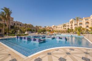 a large swimming pool in a resort with palm trees and buildings at Grand Palace - Adults only 18 years plus in Hurghada