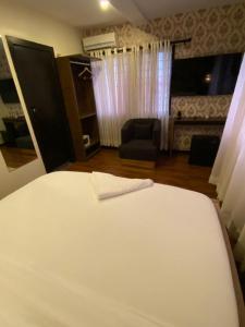 a bedroom with a white bed and a chair at KAFT2 HOTELS in Ijebu Ode