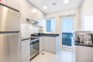 a kitchen with white appliances and a large window at Luxurious Home in Silicon with Stylish Interior in Dubai