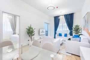 a living room with white furniture and blue curtains at Luxurious Home in Silicon with Stylish Interior in Dubai