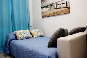 un divano blu con cuscini e una foto sul muro di Appartamento La Pelosa a Stintino