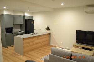 a living room with a kitchen with a counter and a tv at ZMITH Apartment - BROOKE Canberra in Belconnen