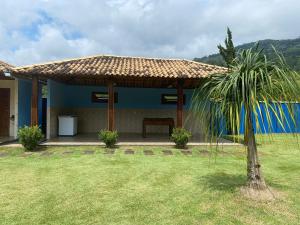 une maison bleue avec un banc et un palmier dans l'établissement Pousada clair, à Ibitirama