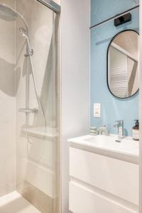 een badkamer met een douche, een wastafel en een spiegel bij 2-BR Haven in Antwerp in Antwerpen