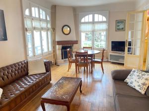 a living room with a leather couch and a table at Villa Soleil Levant in Deauville